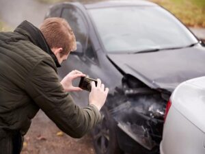 Insurance adjuster taking photos of a car crash.