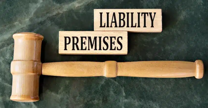A wooden judge's gavel laying beside two stacked wooden blocks labeled "Premises and Liability" on a green marble surface directly illustrating the legal concept of premises liability in personal injury law at Hartley Rowe & Fowler P.C. in Georgia.