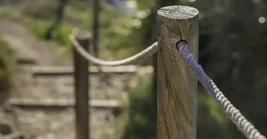 A worn wooden post with a rope railing lining an uneven outdoor stairway path represents the kind of poorly maintained property hazard that can result in a premises liability lawsuit when a visitor is injured within Georgia.